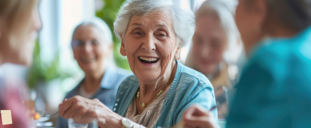 A female senior at a table with friends enjoying the benefits of assisted living